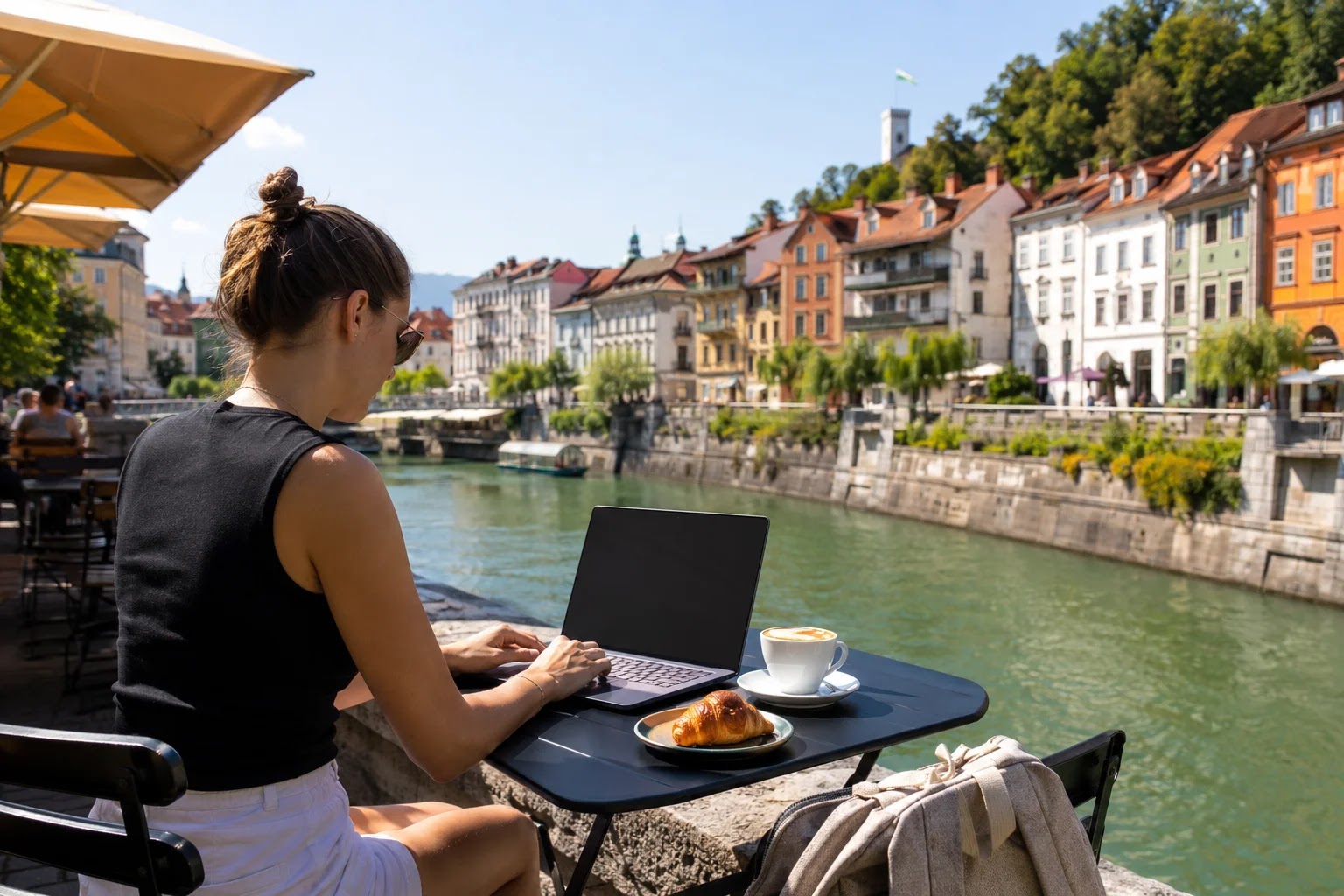 Digital nomad working on a laptop at a riverside cafe terrace in Ljubljana